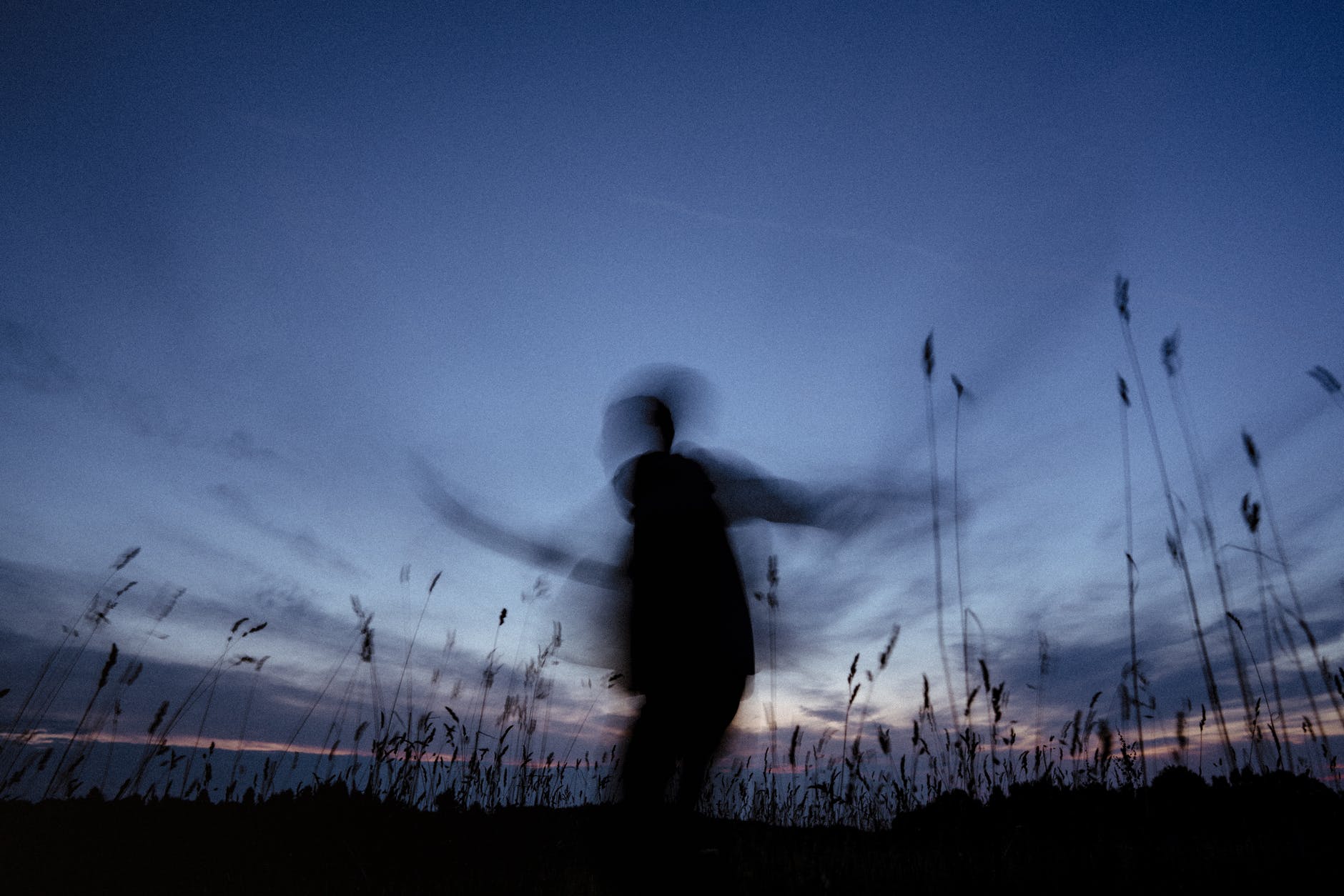 silhouette of man standing on grass field during night time