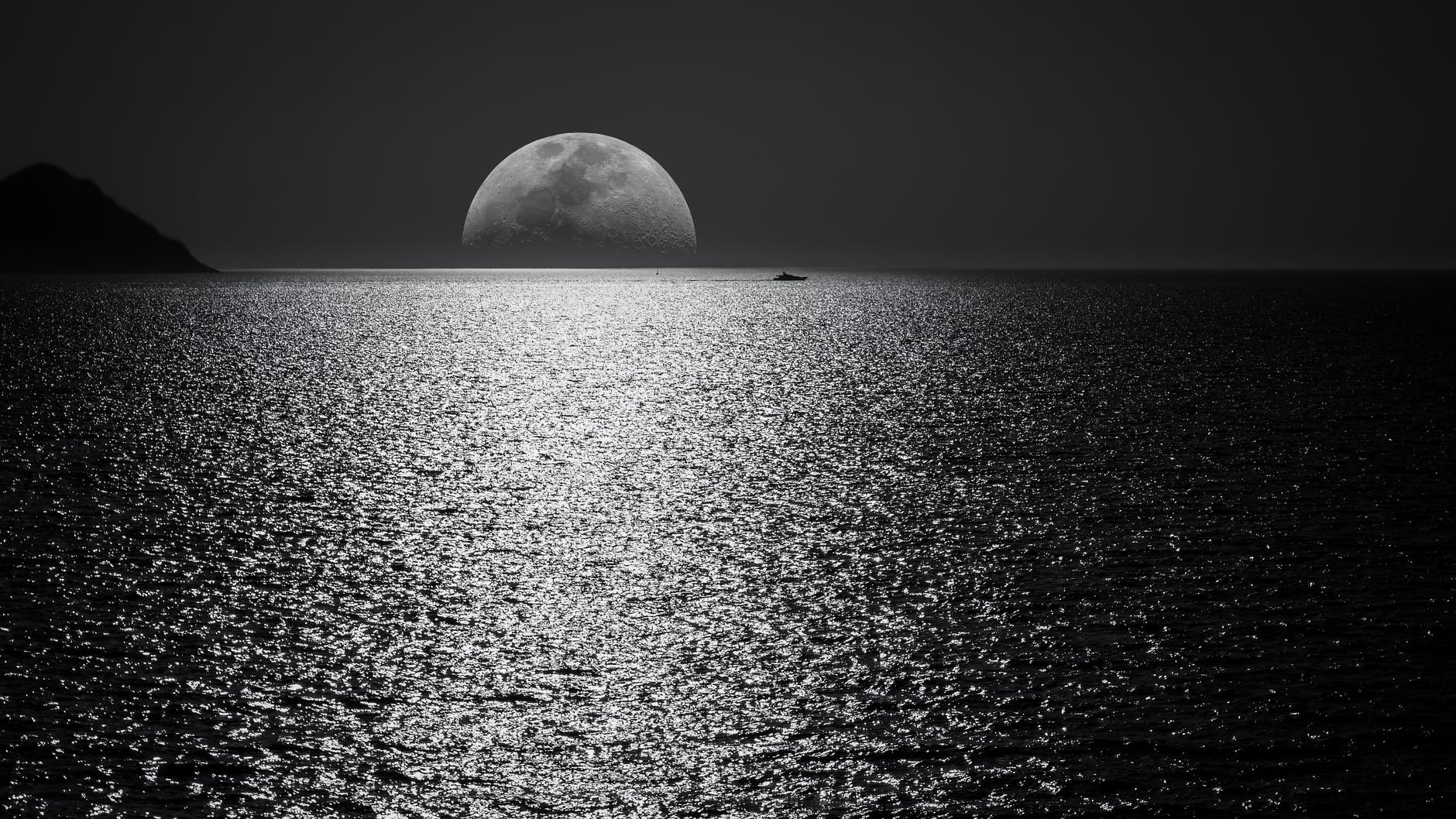 white and black moon with black skies and body of water photography during night time